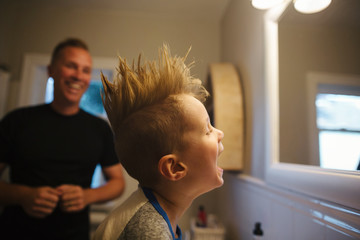 Dad having fun styling little boy's hair into surprising mowhawk