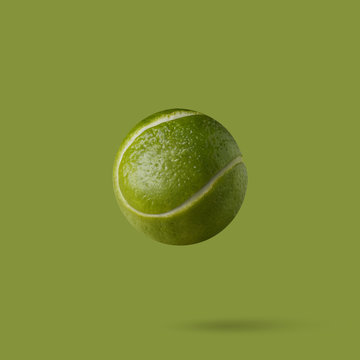 Tennis ball made of lime on a green background with copy space.