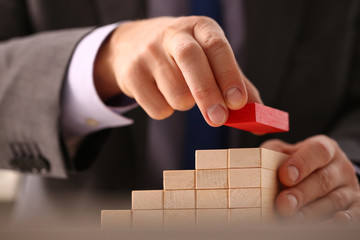 Male hand holds red wood block of stair finish next step rare progress personnel talent authority...