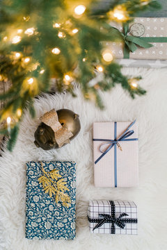 Christmas lights on tree with presents and old-fashioned metal piggy bank on the carpet underneath it