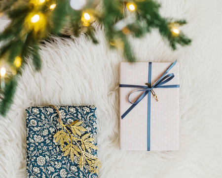 Gifts with golden ornaments under Christmas tree with lights