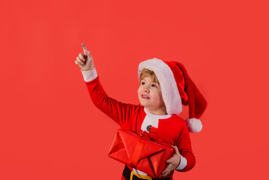 Gift. Santa helper. Elf. Little klid in Santa costume holds presetn. Santa Claus. Gifts. New Year. Happy New Year. Christmas. Eve. Holiday. Kid in santa hat. Christmas. New year kid. Close up.
