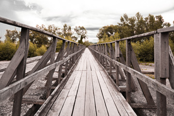 Winding wooden bridge over a river old in deep forest, natural vintage background