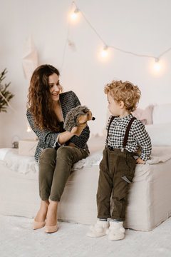 Woman showing toy swab to boy near bed in decorated room