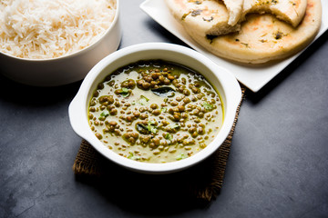 Black Masoor Dal fry or Dhaba Style Sabut Red Lentil dhal tadka in green curry, served in a bowl. selective focus