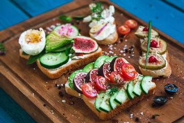 two sandwiches and two bruschettas on a wooden cutting board