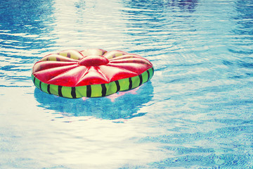Fototapeta na wymiar Inflatable ring in the shape of a watermelon on the surface of the water in the pool