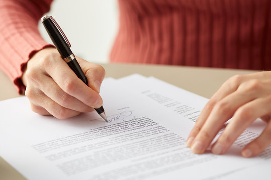 Crop woman signing paper agreement