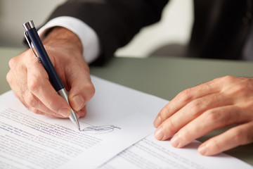 Businessman putting signature on agreement paper