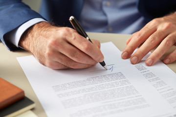 Faceless man signing paper