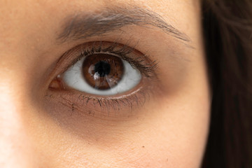 An extremely detailed and macro view on the eyeball of a woman with dark brown marbled iris, dark...