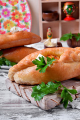 Rasstegai pie of yeast dough with meat filling on white wooden table. Traditional meal of Russian cuisine