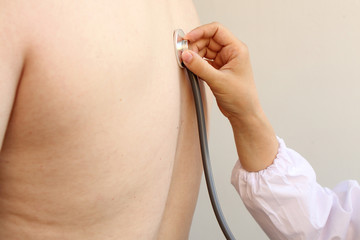 partial photograph of a doctor's girl with a stethoscope in a professional medical uniform examining a patient