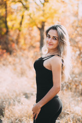 Beautiful attractive girl posing in autumn forest in black pants and t-shirt with beautiful white hair