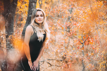 Beautiful attractive girl posing in autumn forest in black pants and t-shirt with beautiful white...