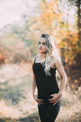 Beautiful attractive girl posing in autumn forest in black pants and t-shirt with beautiful white...