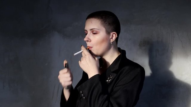 Bald girl lights a cigarette and smokes