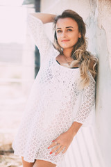 Fototapeta premium Beautiful and sexy girl in a white light dress on a bright Sunny day next to the old staircase