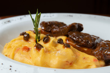 Delicious braised beef roast with creamy mashed potatoes. Loin with coffee and mashed potatoes. Wooden background. Close up.