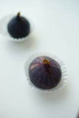 Two ripe sweet figs in paper and white table. Selective focus