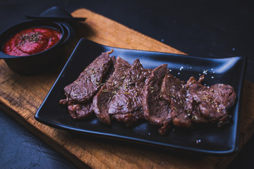 Rolled beef steak with tomato sauce on cutting wood.