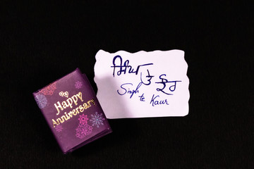 Hand written couple name initials on white paper and happy aniversary mini message book on dark...
