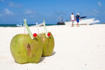 Coconut drink on beach, unrecognizable people walking along sea shore in the background, Punta Cana, Dominican Republic