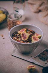 Homemade healthy granola with fresh figs and honey drizzle in a breakfast bowl on pink table.