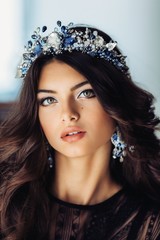 Portrait of beautiful brunette woman in crown with makeup in fashion black clothes