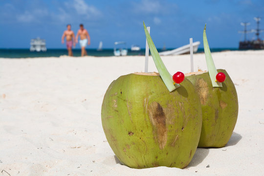 Coconut drink on beach, unrecognizable people walking along sea shore in the background, Punta Cana, Dominican Republic