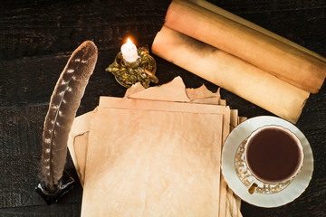 A cup of drink, scroll of papyrus, feather, and candle in a candlestick