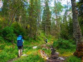 A group of tourists with backpacks walking a beautiful mountain path.