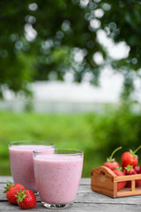 A glass of fresh cold smoothie with berries and cherrys on a wooden table, summer set, outdoor greed blured background,boke.