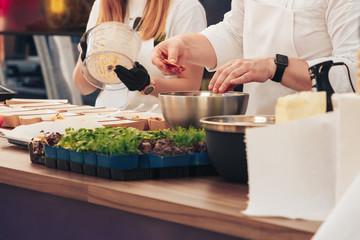 Chef prepares many servings of food next to the assistants