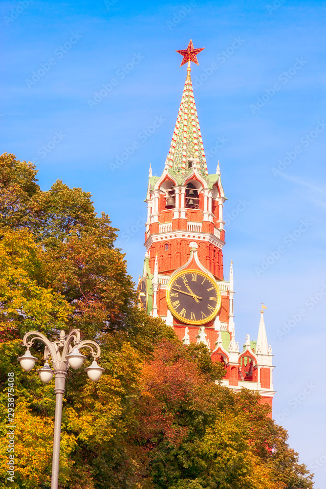 Wall mural The Spasskaya Tower, or 'Saviour Tower', is the main tower on the eastern wall of the Moscow Kremlin which overlooks the Red Square. View from the autumnal trees.