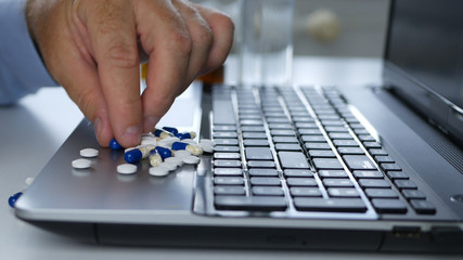 Suffering Person In Office Select Medical Pills on the Laptop Surface