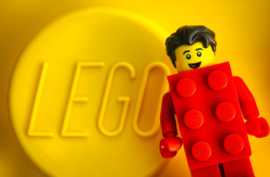 Tambov, Russian Federation - May 20, 2018 Lego Red Suit Brick Guy minifigure against yellow background with word LEGO. Studio shot.