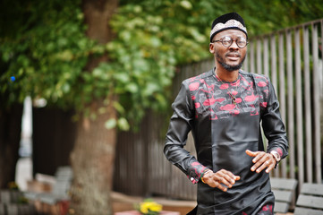 Handsome afro american man wearing traditional clothes, cap and eyeglasses in modern city.