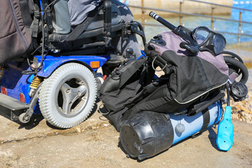 Handicapped disabled scuba diver with equipment on a beach shore looking at sea