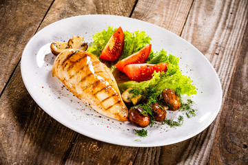 Grilled chicken fillet and vegetables on white plate
