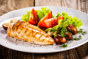Grilled chicken fillet and vegetables on white plate