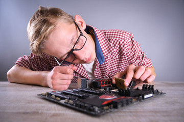 Man repairing broken computer, video card,memory RAM, cooler, processor,hard drive. Young repairer working with screwdriver in service center.teenager