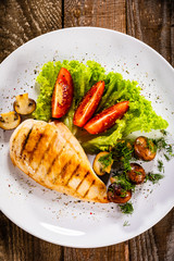 Grilled chicken fillet and vegetables on white plate