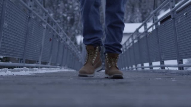 classic boots walking over alpine steel bridge serfaus