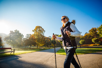 Nordic walking - middle-age woman working out in city park