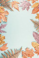 Autumn composition with golden leaves frame on blue pastel background. Fall mockup with gold maple leaves. Flat lay, top view, copy space