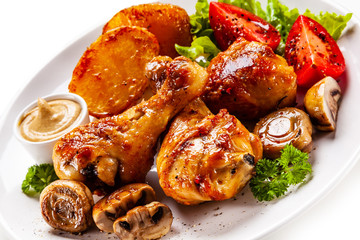 Grilled chicken drumsticks with baked potatoes and vegetables