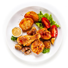 Grilled chicken drumsticks with baked potatoes and vegetables