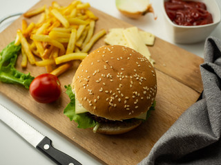 Domowe burgery z dodatkami. Mięso, bułka, pomidor, frytki, ketchup. Jasne tło. - obrazy, fototapety, plakaty