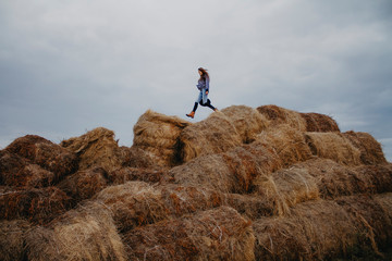 Naklejka na ściany i meble A child runs along haystacks.